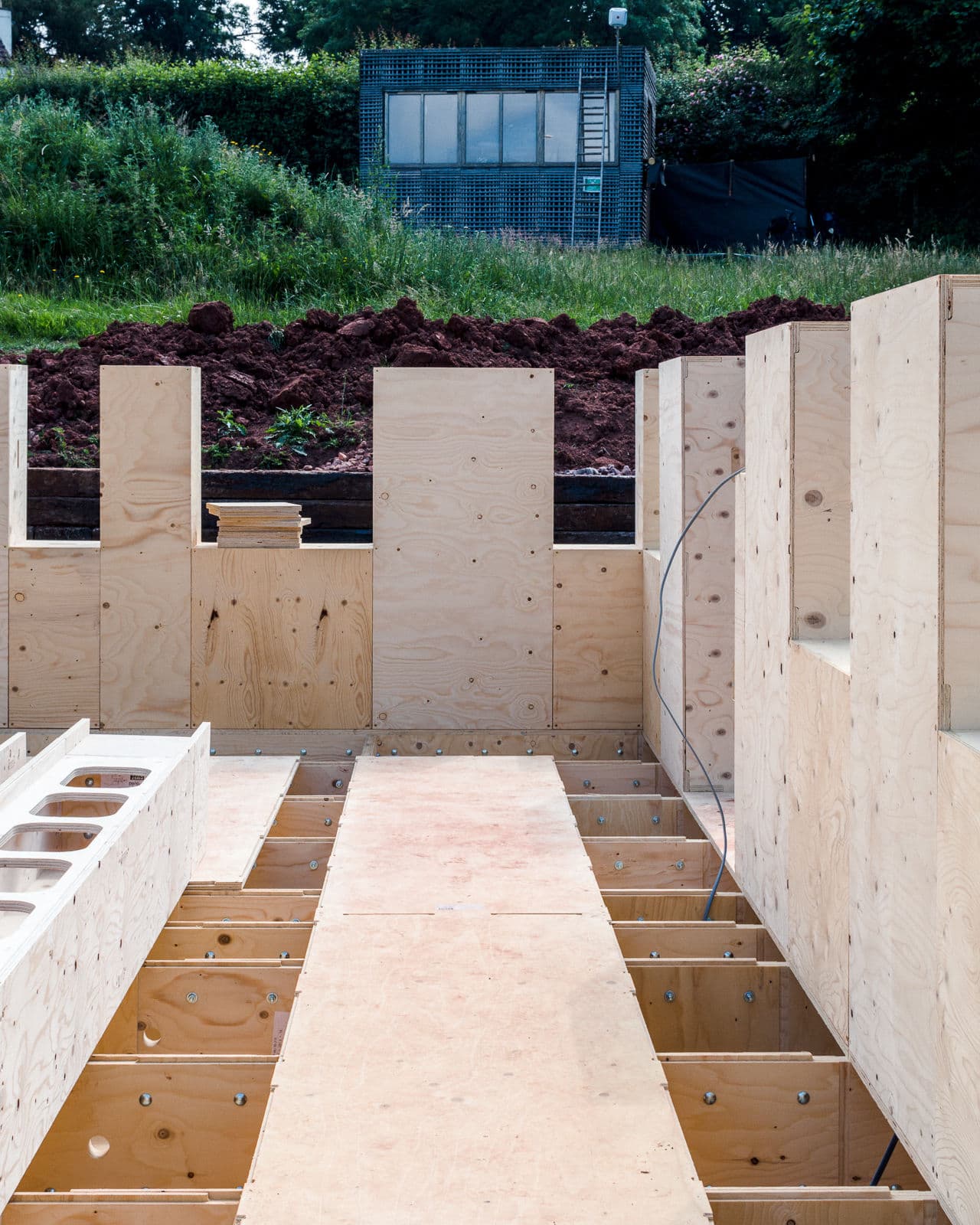 Architectural project - plywood walls, open sky, rural site, CLT walls, framework, exterior perspective, building progress, natural materials, raw materials, timber frame, modular construction, prefabricated building, eco design, green building, contemporary architecture, construction phase, construction site, modern construction, site work, plywood, outdoor construction, construction project, building site, beige, brown, light wood, natural wood, engineered wood, timber construction, honey wood, wood construction, sustainable building, cross laminated timber, groundwork, green architecture, earthworks, green setting, passive house, landscape integration, earthy tones, structural elements, building development