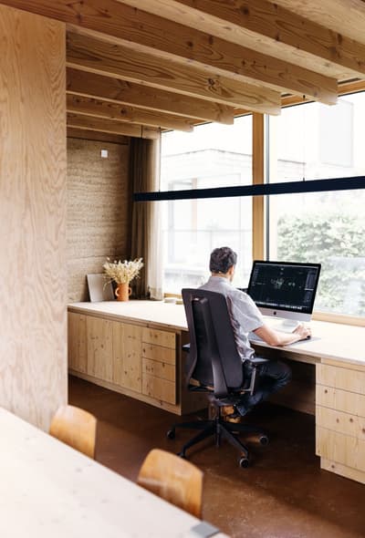 Architectural project - modern workspace, contemporary office, cozy office, timber desk, relaxed environment, wood desk, natural materials, eco-friendly design, wood, timber, raw materials, natural light, warm tones, neutral tones, exposed beams, daylight, plywood, beige, brown, light wood, modern design, simple design, honey wood, Scandinavian style, minimalist style, timber walls, biophilic design, clean lines, Nordic design, large window, wooden interior, wood walls, timber ceiling, warm ambiance, inviting space, earthy tones, garden view, home office, comfortable chair, work from home, wood ceiling, floor-to-ceiling window, sustainable interior, organic textures, bright room