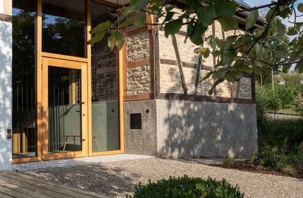 Architectural project - exposed timber, light grey, earthy design, timber details, open entrance, stone house, farmhouse aesthetic, pastoral charm, historic style, natural materials, wood, timber, outdoor space, timber frame, passive design, glass, sustainable architecture, neutral tones, light wood, eco friendly, natural setting, wooden beams, rustic charm, green architecture, eco home, cozy vibe, large window, textured wall, energy efficient, stone, nature-inspired, stone wall, rustic facade, rustic architecture, heritage building, garden view, traditional style, countryside living, gravel path, wooden elements, warm exterior, glass door, rural house, country home