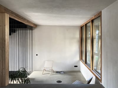 Architectural project - floor to ceiling windows, raw elegance, woven chair, muted colors, potted plant, minimalist room, airy vibe, quiet space, filtered light, relaxing nook, reading chair, serene room, inviting vibe, open feeling, natural materials, natural light, sustainable design, light wood, eco friendly, Scandinavian influence, simple design, natural textures, cozy retreat, neutral palette, tranquil setting, contemporary home, modern minimalism, clean lines, white walls, light filled, large windows, architectural simplicity, wood frame, timber accents, beige tones, airy space, plaster finish, cozy corner, modern home, calm atmosphere, interior space, peaceful atmosphere, Japandi style, indoor plants, residential interior